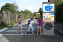 Spielende Kinder bei der Einfahrt in eine Begegnungszone. Das Torelement mit dem Signal sowie die dazugehörenden Markierungen gehören zum Standard jeder Begegnungszone.